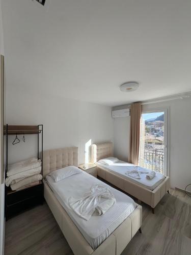 two beds in a room with a window at Hotel SKURA , Librazhd in Librazhd