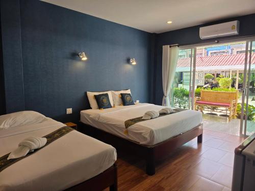 two beds in a room with blue walls and a window at Near the Beach Cha-Am in Cha Am