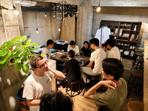 a group of people sitting at tables in a room at ArtBar & GuestHouse ennova in Atami