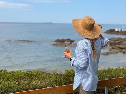 a woman wearing a straw hat taking a picture of the ocean at Cedrus-Seafront Ionian Stay in Agios Georgios