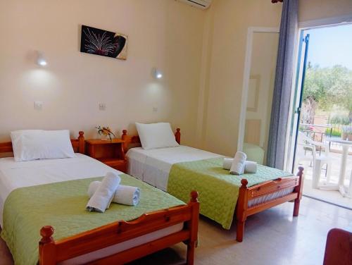 a bedroom with two beds and a large window at Nikos Apartments 1 in Kavos
