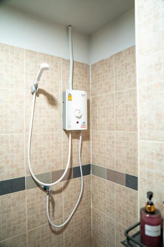 a shower in a tiled bathroom with a hose at Bud Brew Beyond Dispensary and Hotel in Bangkok