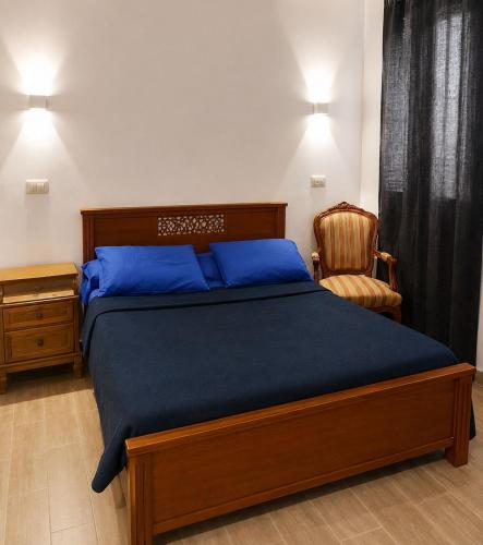a bedroom with a bed with blue sheets and a chair at فيلا التجاريين in Dawwār ‘Abd Allāh