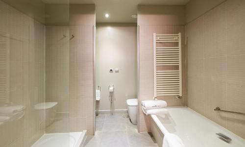 a bathroom with a tub and a toilet and a sink at Hotel Spa Attica21 Vilalba in Villalba