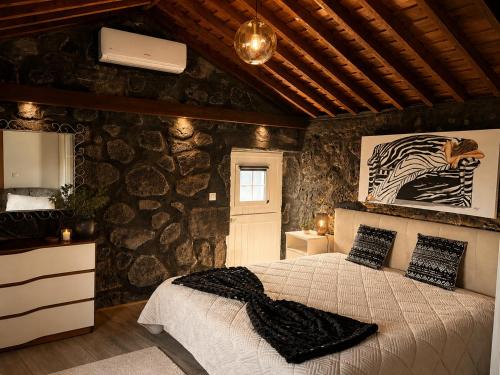 a bedroom with a bed and a stone wall at Casinha de Pedra in Cais do Pico