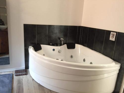 a white bath tub in a bathroom with black tiles at L'éphémère-Private Spa in Plérin