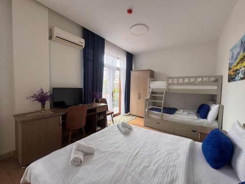 a bedroom with two beds and a desk with a computer at Hotel Port Altus in Batumi