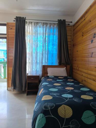 a bedroom with a bed with a blue comforter at Zen Homestay in Dirang Dzong