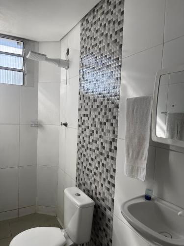 a white bathroom with a toilet and a sink at House farol in Aracaju