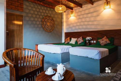 a bedroom with two beds and a table and a chair at Knuckles Retreat in Huluganga