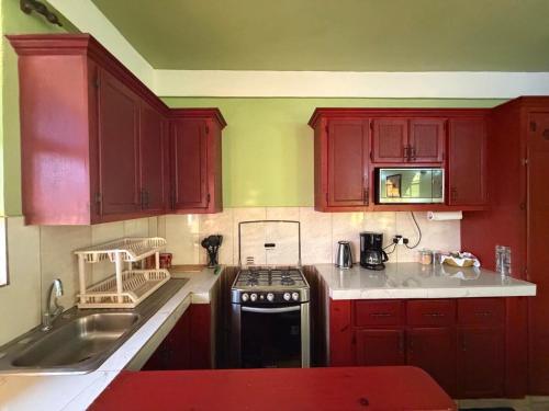 a kitchen with red cabinets and a stove top oven at 2BR Guest Home - Dominica in Pointe Michel