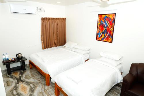 two beds in a room with white sheets at Shri Valli Rooms in Tiruvannāmalai