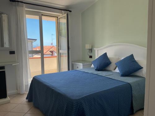 a bedroom with a blue bed and a balcony at Hotel Ristorante Colleverde in Santa Maria di Castellabate