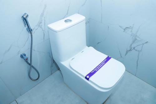 a bathroom with a toilet with a shower head at Shri Valli Rooms in Tiruvannāmalai