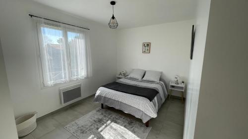 a white bedroom with a bed and two windows at Maison Eguilles in Éguilles