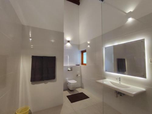 a white bathroom with a sink and a toilet at Parrot Paradise Negombo in Negombo
