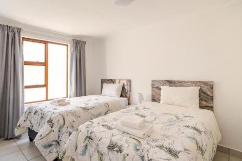a bedroom with two beds and a window at Sintha Guesthouse in Kraaifontein