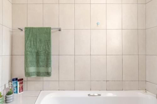 a bathroom with a green towel hanging over a tub at Sintha Guesthouse in Kraaifontein