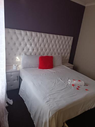 a bedroom with a white bed with a red pillow at Fourways guesthouse & spa in Fourways