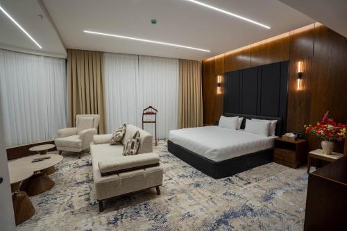 a hotel room with a bed and a couch and chairs at Grand Babl in Erbil