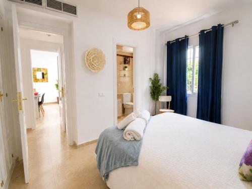 a bedroom with a large white bed with blue curtains at Cristina Bungalow in Estepona