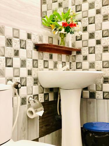 a bathroom with a white sink with a vase of flowers at Golden Breeze Arugambay in Arugam Bay