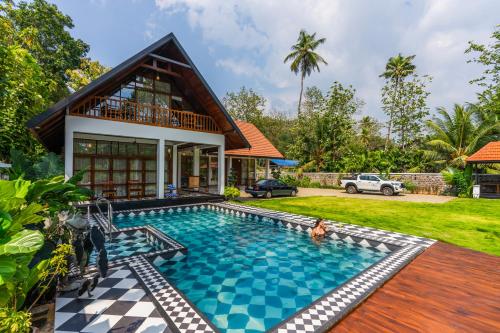 a villa with a swimming pool and a house at K Manor in Vāzhākulam