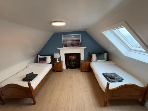 a attic room with two beds and a fireplace at Nook and Scranny in Tarbert