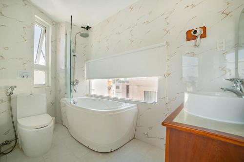 a bathroom with a tub and a toilet and a sink at Art Deluxe Hotel in Nha Trang