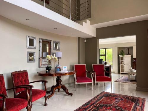 a living room with red chairs and a table at Alabaster Luxe Villa in Langebaan