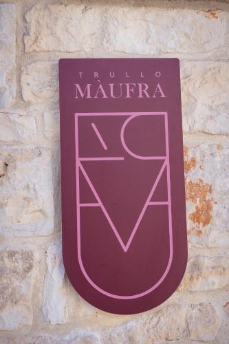 a purpleangular sign on a stone wall at Trullo Màufra in Locorotondo