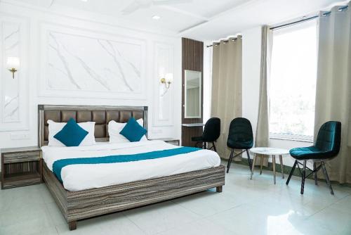 a bedroom with a bed with blue pillows and chairs at Hotel SP Grand Near Mohali Bus Stand & Civil Hospital in Mohali