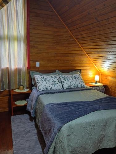 a bedroom with a bed and a wooden wall at Cabana mandaçaia in Timbe do Sul
