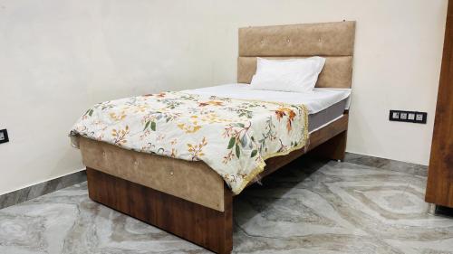 a small bedroom with a bed with a flowery blanket at Hotel Sangree in Jewar