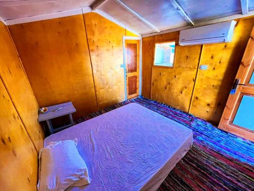 a small bedroom with a bed in a wooden room at Galuma magbul camp in Dahab