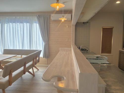 a living room with a table and a kitchen at Private Rock Onsen Villa Orin & Zen Garden in Shiraoi