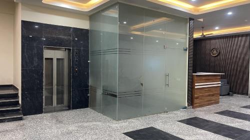 a glass wall in a lobby with a elevator at Hotel Sangree in Jewar