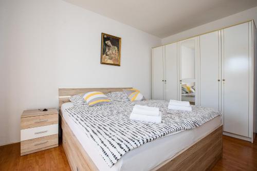 a white bedroom with a large bed and a dresser at Apartments Fabijanić in Rab