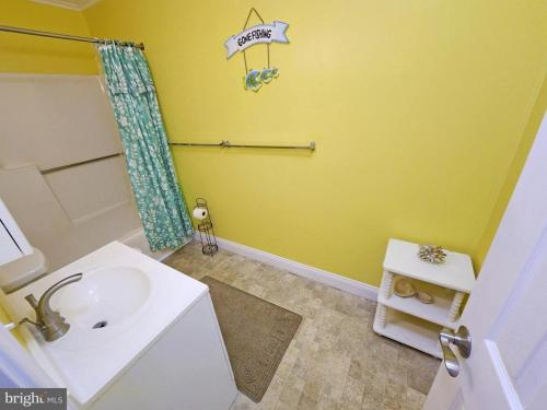 a yellow bathroom with a sink and a shower at Beach Condo in Ocean City, MD in Ocean City