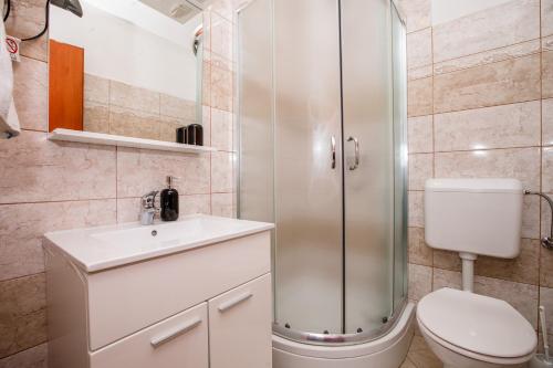 a bathroom with a shower and a toilet and a sink at Apartments Fabijanić in Rab