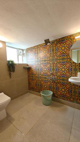 a bathroom with a toilet and a tile wall at Casa pinto Valencia and The Second Storey in Mangalore