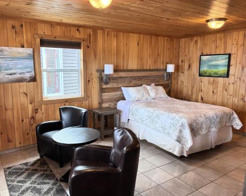 a bedroom with a bed and chairs in a room at Augustus Jane Inn in Rocky Harbour