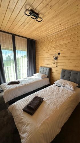 two beds in a room with wooden walls and windows at Шервуд in Myta