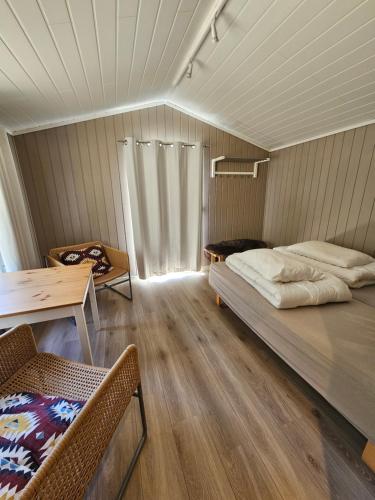 a room with a bed and a table and chairs at Dalen Gaard camping og hytter in Geiranger