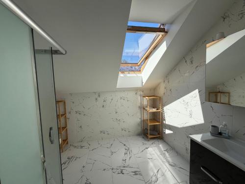 a bathroom with a skylight and white marble walls at SC Apartments Bad Goisern - contactless check in in Bad Goisern