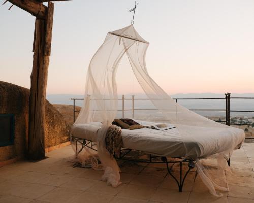 a bed with a mosquito net on a balcony at Beit Al Fannan in Ţabaqat Faḩl
