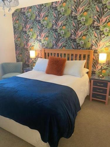 a bedroom with a blue bed with a floral wallpaper at The Royal George Cottingham in Cottingham
