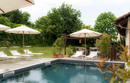 a swimming pool with chairs and umbrellas next to at Braja in Sommariva del Bosco
