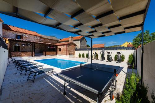 an outdoor patio with a pool table and chairs at Villa Dora with heated pool & fitness in Gradina
