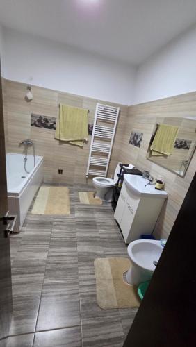 a bathroom with two toilets and a sink and a tub at Casă in Năvodari